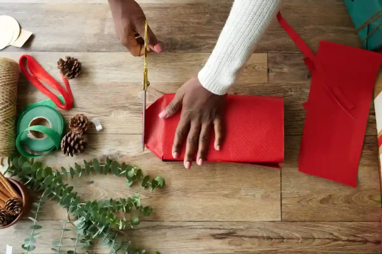 Une personne qui emballe un cadeau avec du papier cadeau rouge