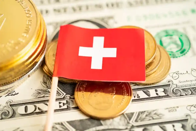Un petit drapeau suisse posé sur des piles d'argents