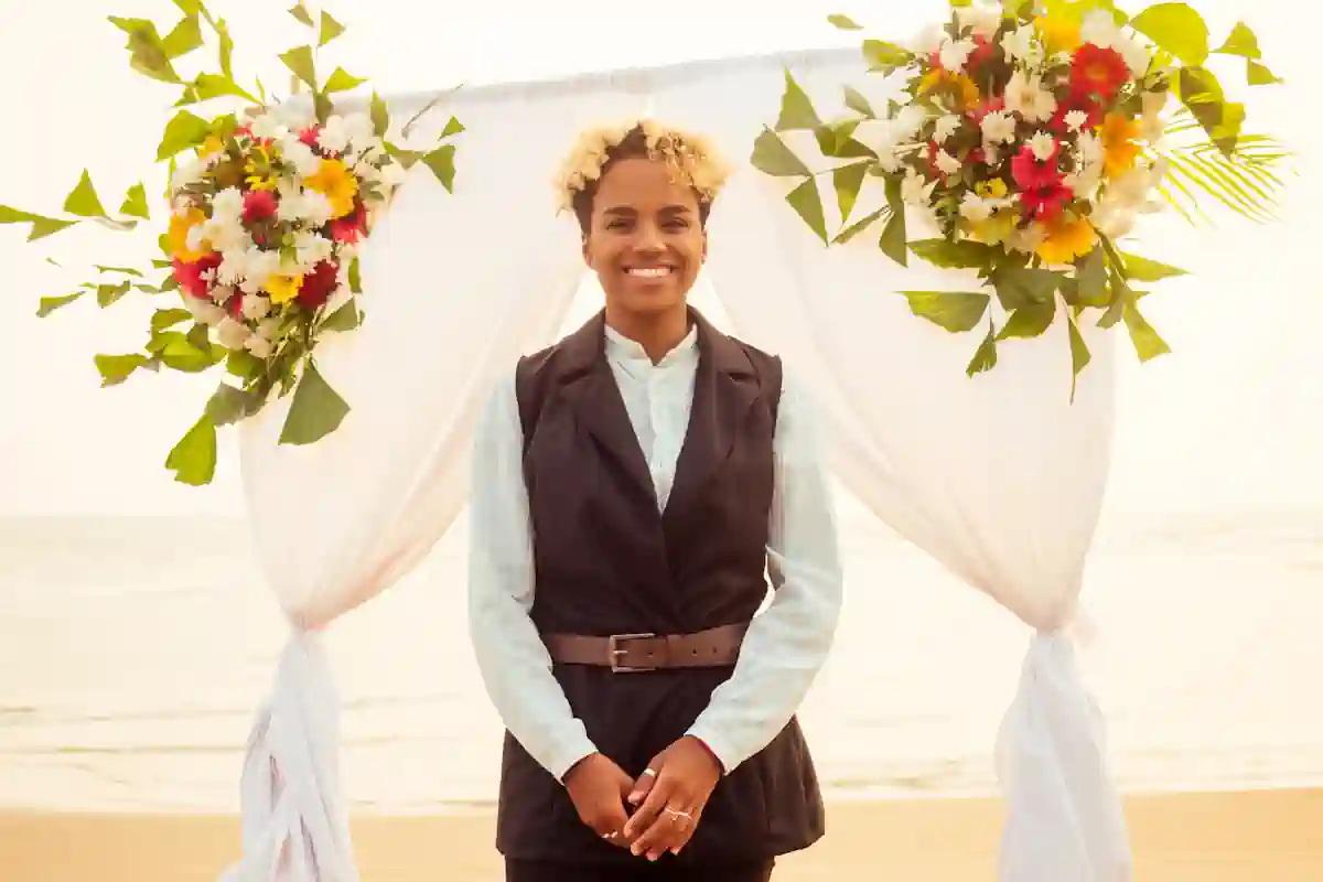 Une jeune femme souriante debout devant une arche en voile et en fleurs