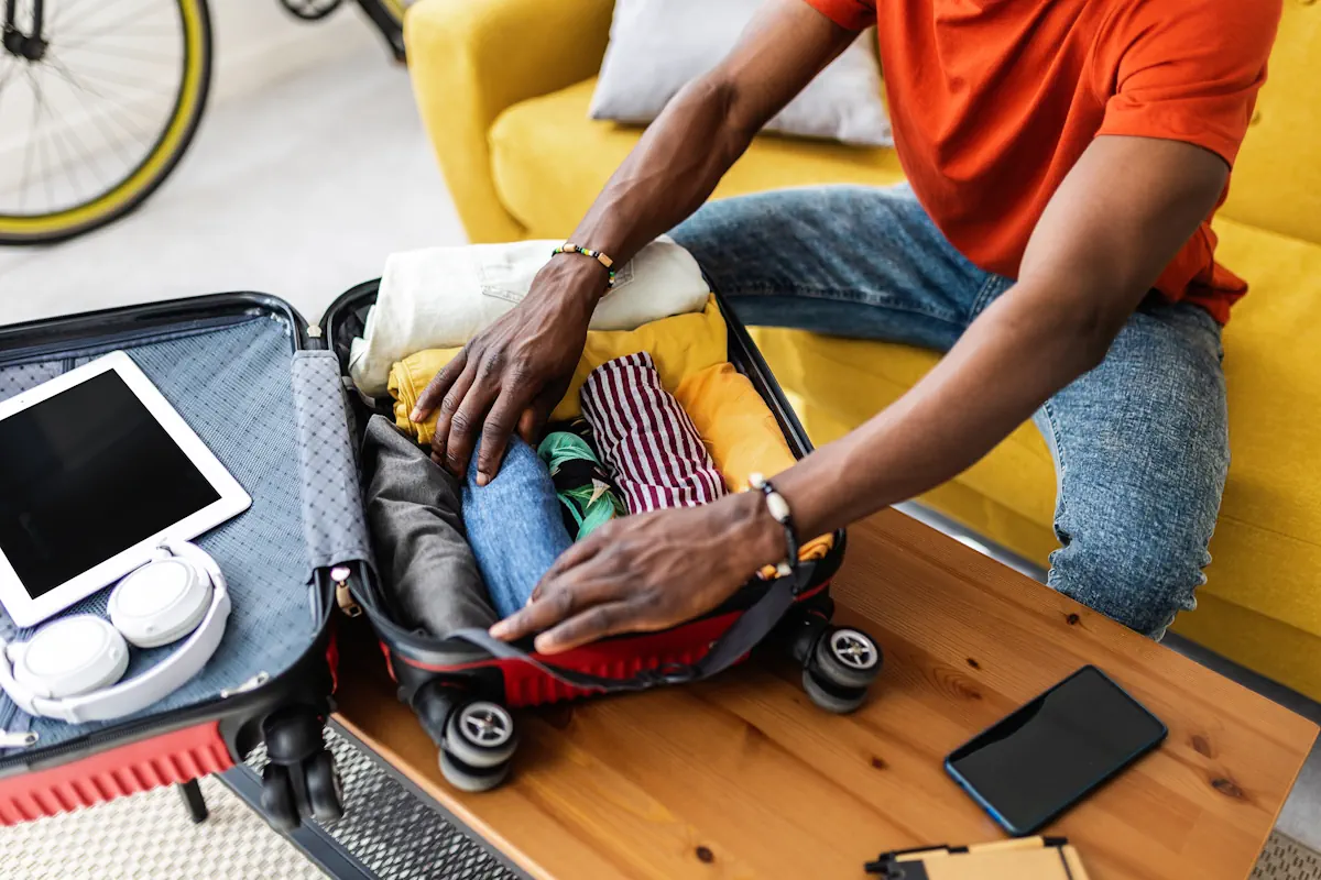 Un homme qui roule ses vêtements dans une valise