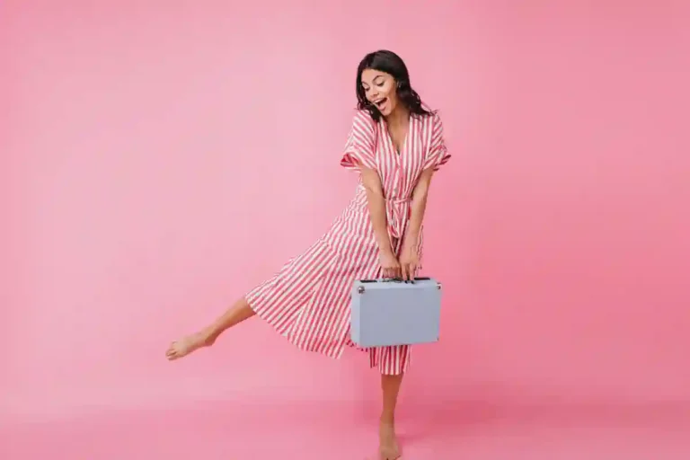 Une femme en robe qui tient une petite valise