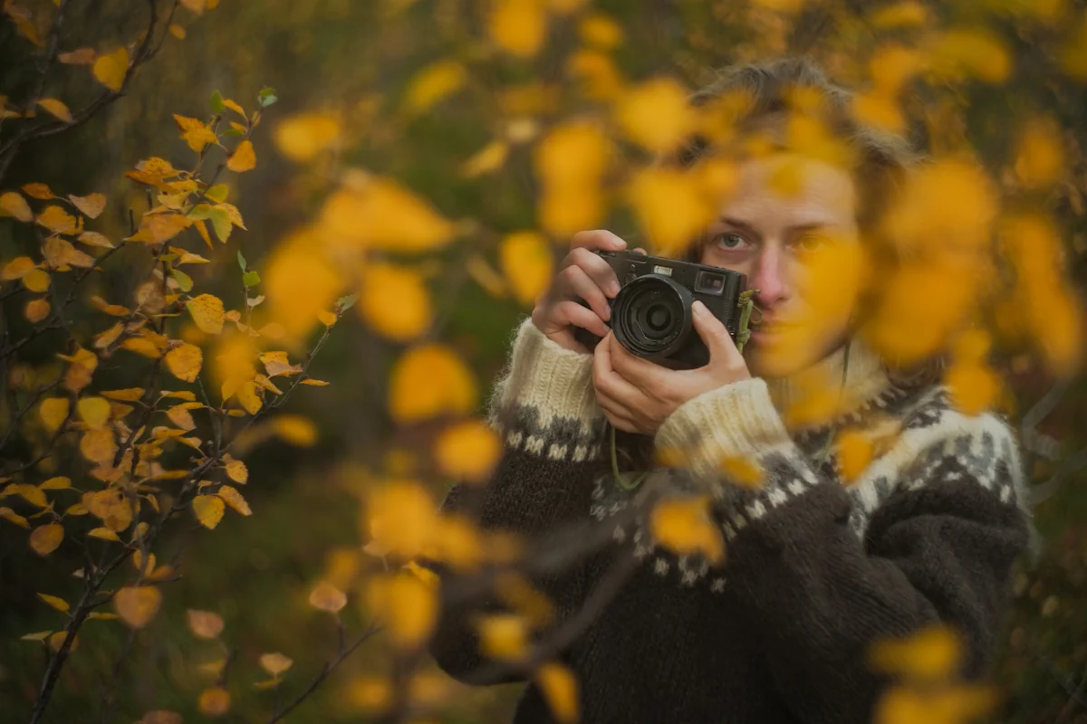Une jeune femme avec un appareil photo qui prend des clichés des feuilles jaunes
