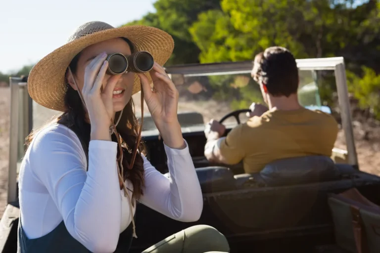 Une femme qui regarde à travers des jumelles pendant qu'un homme conduit une voiture devant