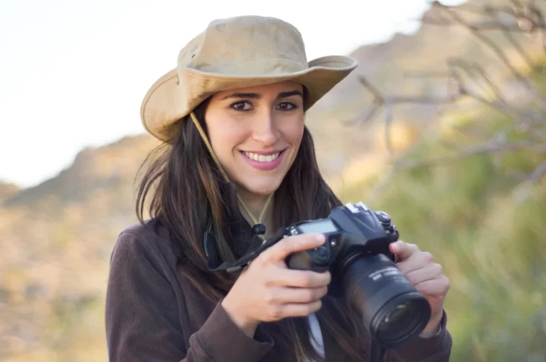 Une femme qui tient un appareil photo dans sa main en portant un chapeau de safari