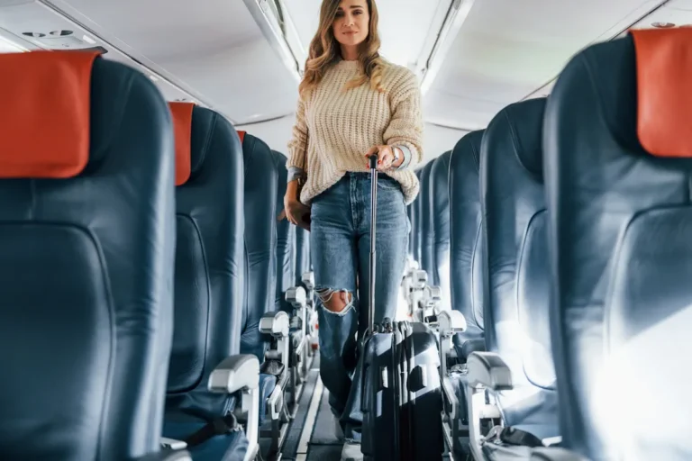 Une femme qui marche avec sa valise dans les couloirs de la classe économique d'un avion