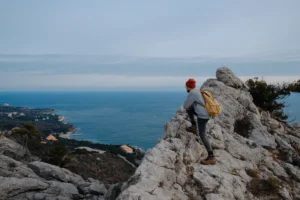 Un homme qui regarde la mer depuis une formation rocheuse en hauteur