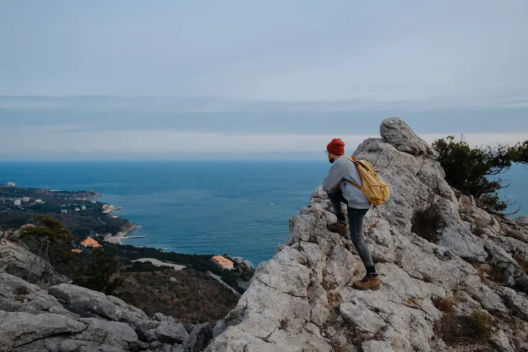 Un homme qui regarde la mer depuis une formation rocheuse en hauteur
