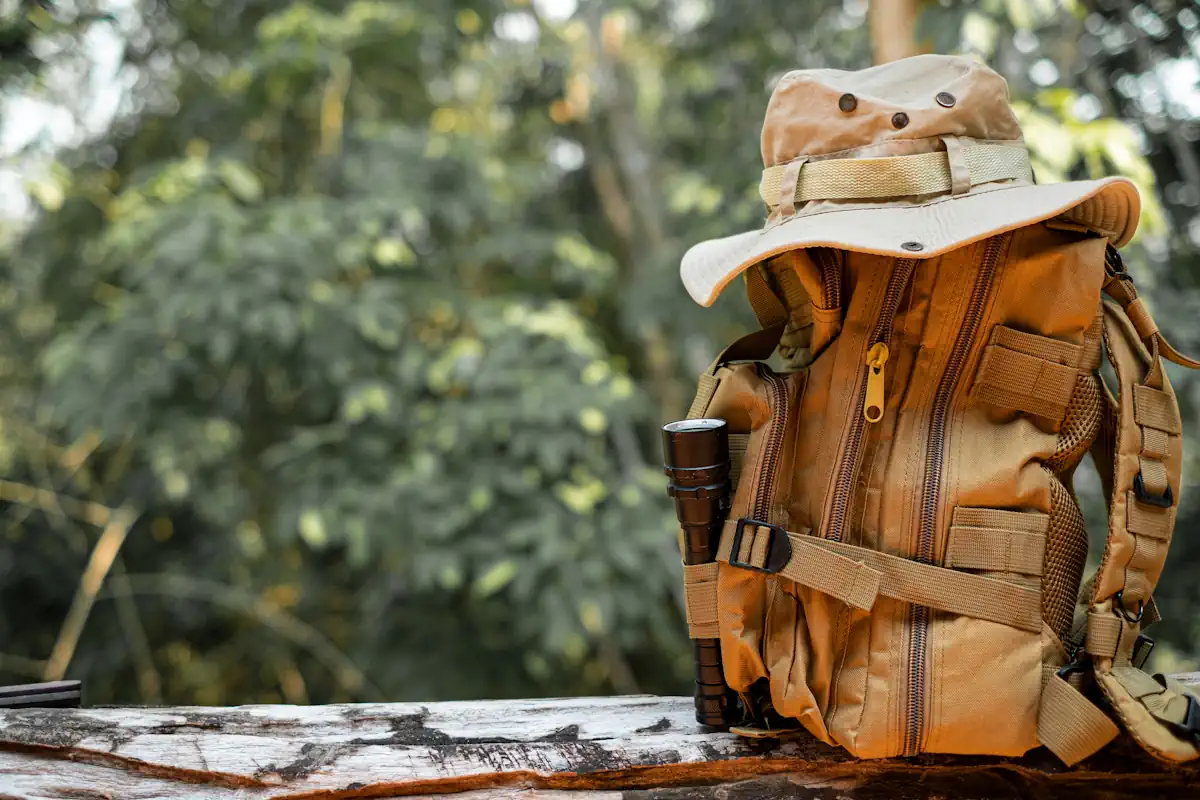 Un sac à dos e un chapeau beige posé sur le sol dans une zone boisée