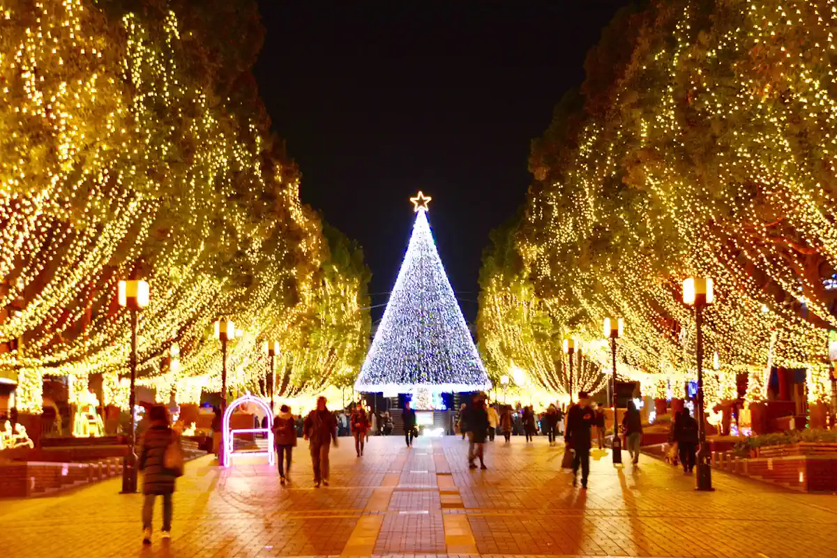 Des arbres décorés avec des guirlandes de Noël sur une plage avec un arbre de Noël illuminé au fond