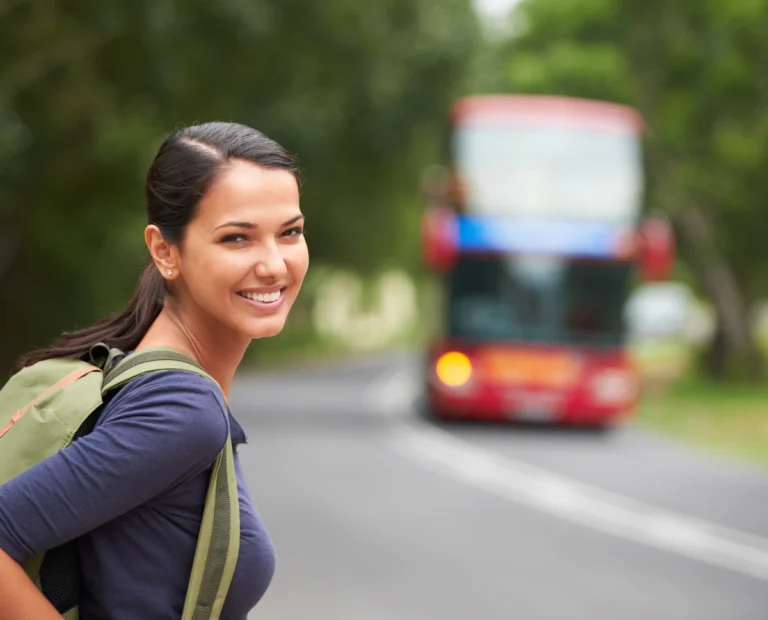 Une femme avec un sac à dos sur le bord de la route avec un bus en approche