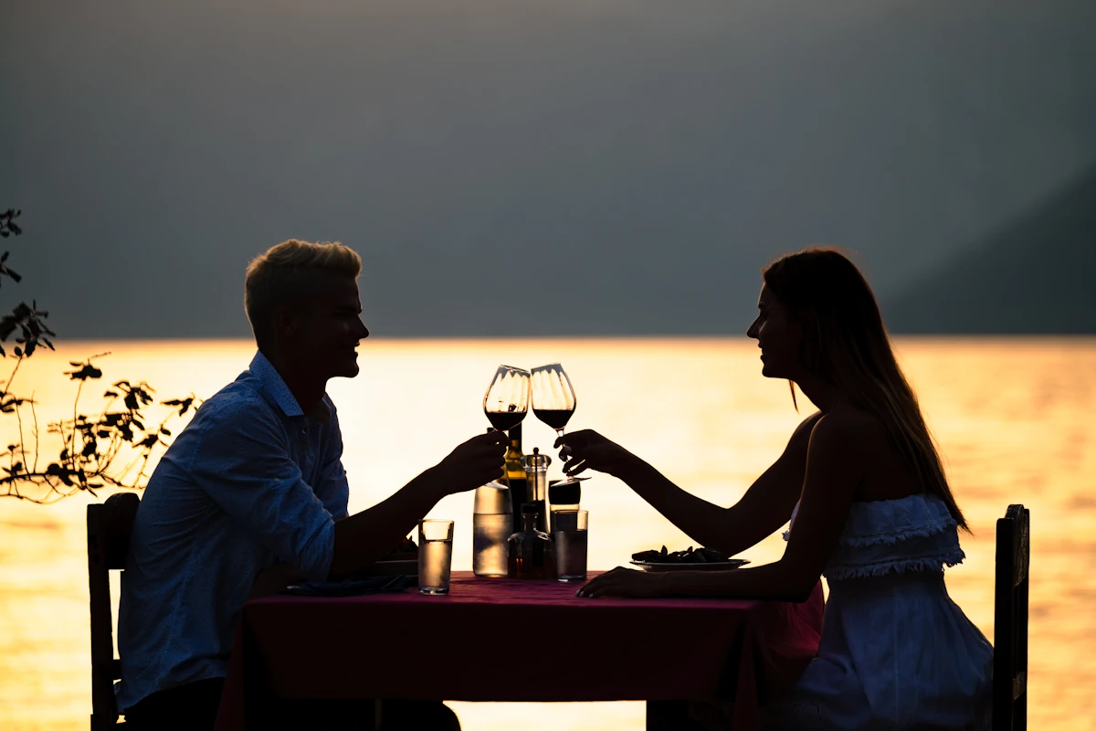 Un couple qui passe un bon moment au restaurant au bord de l'eau au coucher du soleil
