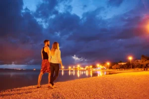 Un homme et une femme qui se promènent sur la plage la nuit