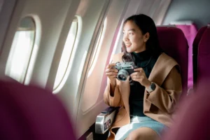 Une femme qui tient un appareil photo assise dans un avion près d'un hublot