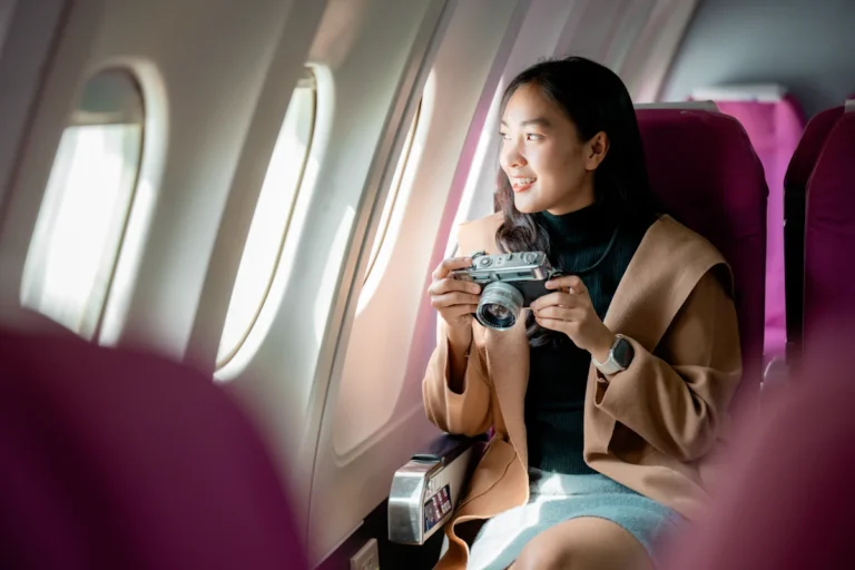 Une femme qui tient un appareil photo assise dans un avion près d'un hublot