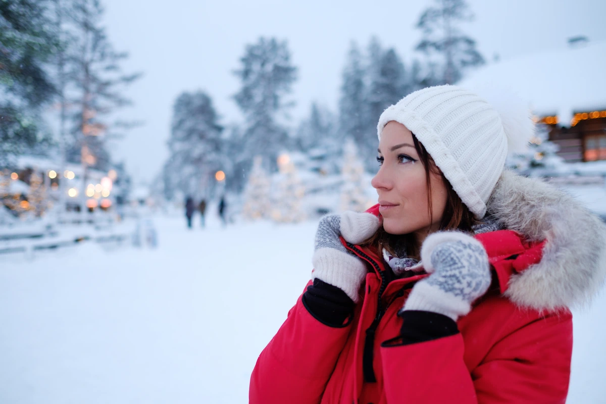 Une femme qui porte un bonnet blanc et des gants ainsi qu'une veste rouge